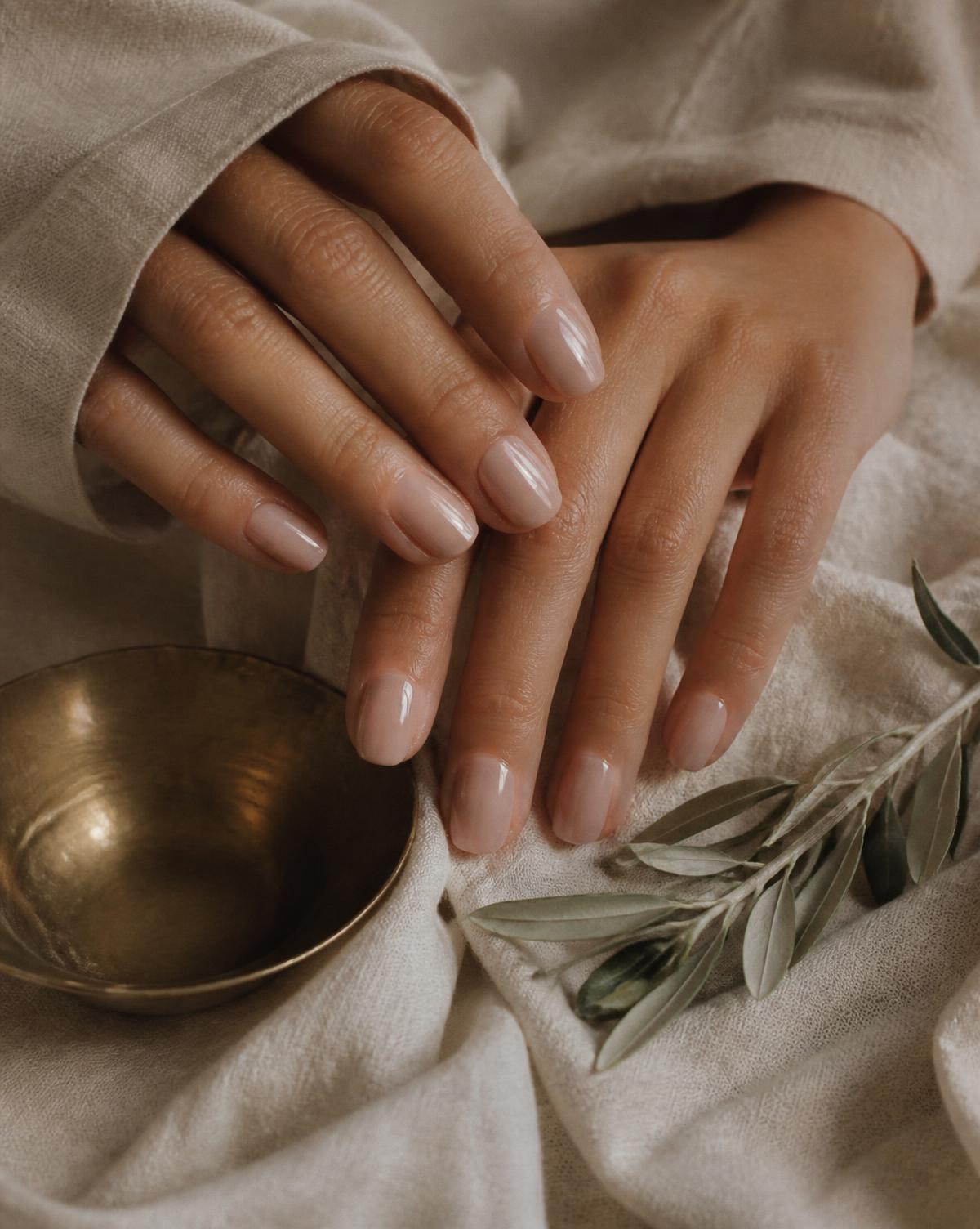 Glossy nude BIAB manicure on folded linen